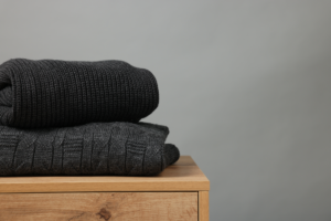 Des vêtements opaques posés sur un meuble en bois