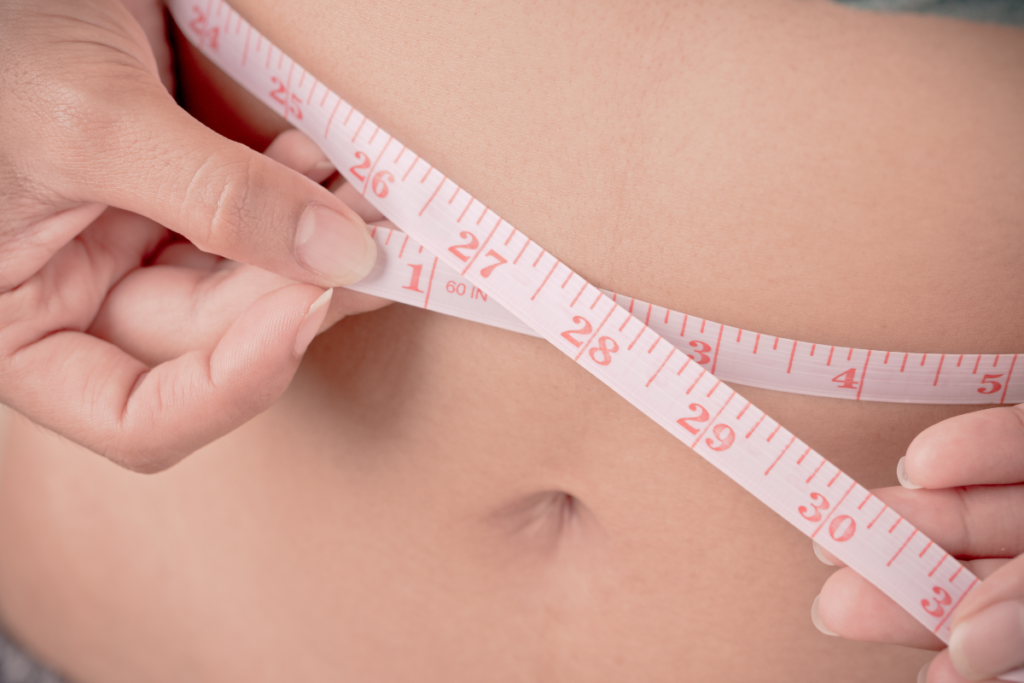 Femme mesurant son tour de taille avec un mètre ruban